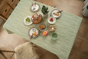 Close-up of match green cotton linen tablecloth with delicate white floral vine pattern