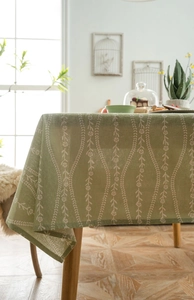 Detailed view of green cotton linen tablecloth with white floral pattern and woven edge