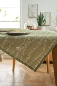 Detail of green cotton linen tablecloth with white floral pattern in a home setting