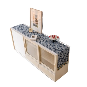 Nordic table runner with blue leaf patterns and colorful tassels on a cream sideboard