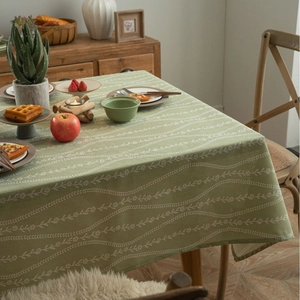 Green linen tablecloth with white floral pattern on a dining table in a cozy home setting