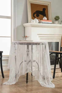 Detail of white lace tablecloth featuring delicate floral patterns and wavy scalloped edges