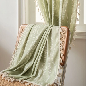 Green pastoral style curtain with white floral print and tassel edges on a wood chair