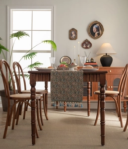 Detailed close-up of vintage jacquard table runner with geometric floral patterns and tassels