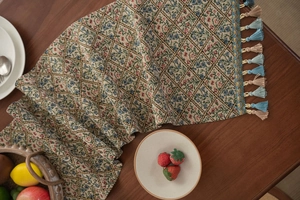 Detailed jacquard fabric texture and tassel fringe of a retro floral table runner