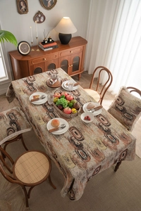 Detail of jacquard tablecloth and matching pillows with orange abstract spiral patterns