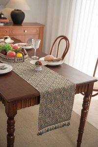 Detailed view of jacquard table runner with floral diamond pattern and tassel fringe
