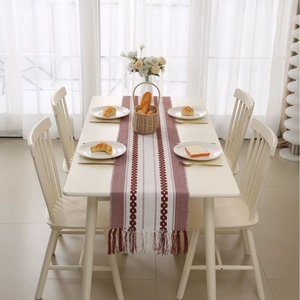 Modern red and white striped table runner with tassels on a minimalist white dining table