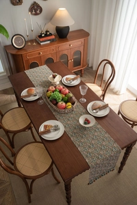 Close-up of floral jacquard table runner with elegant blue tassels on wood table