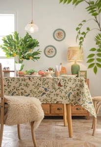 Close-up of jacquard tablecloth featuring realistic birds and green foliage patterns