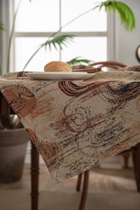 Close-up of heavy jacquard tablecloth with brown and orange abstract wood grain pattern