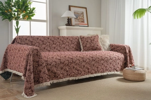 Close-up of wine red jacquard sofa cover with floral texture and cream fringe accents
