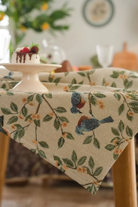 Detail of jacquard floral tablecloth with vintage bird pattern on rustic wooden table