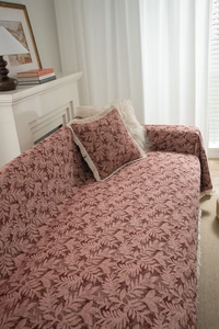 Detail view of brick red leaf jacquard sofa cover and matching pillow with tassels