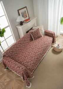 Detail of vintage red floral sofa cover with white tassels and matching pillowcase