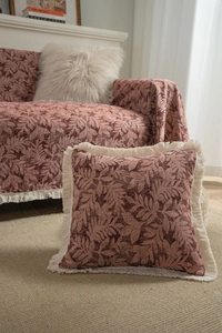 Close-up of red leaf pattern jacquard sofa throw and cushion with creamy white tassels