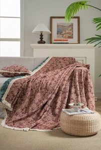 Close-up of vintage red floral jacquard sofa throw with elegant fringe and pillow detail
