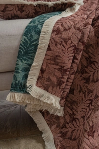 Detail of leaf pattern jacquard sofa throw with long decorative tassels on a sofa