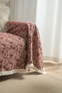 Close-up of pink jacquard sofa throw with leaf patterns and white fringe details