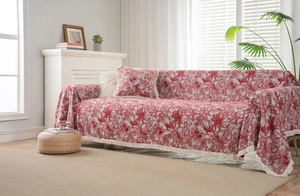 Detail of red floral jacquard sofa throw with beige tassels and matching pillow decor