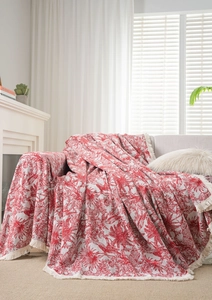 Close-up of red and beige jacquard floral pattern on thick sofa throw with cream tassels