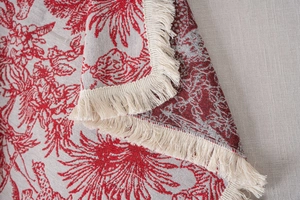 Detailed macro shot of red jacquard fabric showing intricate floral patterns and tassels