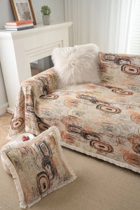 Détail de la housse de canapé jacquard beige et coussin à franges avec anneaux abstraits