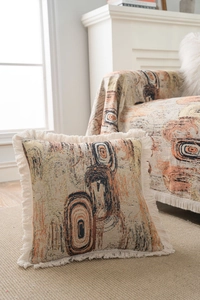 Gros plan sur un coussin jacquard à motifs géométriques avec des franges beiges