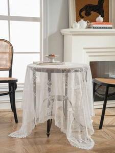 Detail showing the intricate floral lace pattern and scalloped edges of the white tablecloth