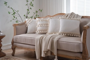 Detailed view of four cream bohemian tassels cotton linen cushion covers on sofa