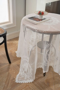 Close-up of elegant white lace tablecloth featuring delicate floral embroidery and scalloped edges