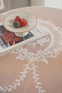 Detail of floral lace tablecloth featuring white jacquard patterns on warm brown fabric