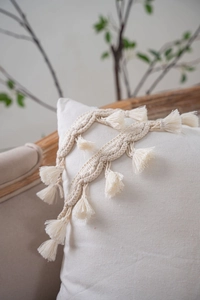 Detailed close-up of bohemian woven throw pillow featuring tassels and textured wheat patterns