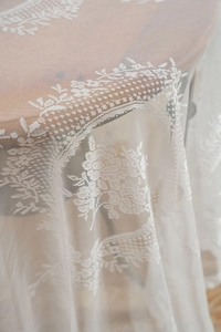 Close-up of white lace tablecloth featuring intricate vintage floral patterns and mesh detail