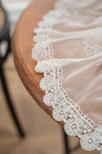 Close-up of white lace tablecloth with floral embroidery on a dark wooden table