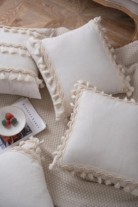 Detail of bohemian cream square cushion cover with textured tassel fringe edges
