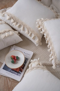 Detail of cream tassel pillowcase with bohemian fringe and woven wave ribbon texture