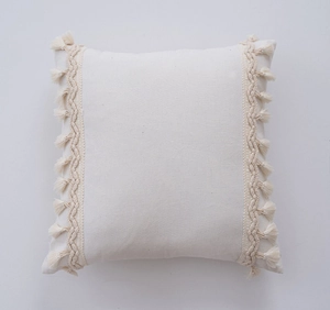 Detail of bohemian ivory cushion cover featuring handmade woven waves and tassel trim edges