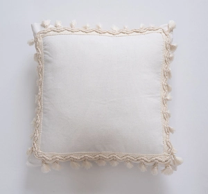 Detail of bohemian cream fringe cushion cover with braided trim and tassel edges