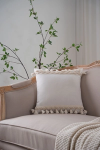 Detail of cream white cotton linen cushion cover with elegant woven lace and fringe edges