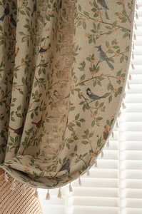 Detail of floral and bird jacquard curtain fabric with white bohemian fringe trim
