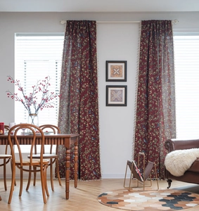 Close-up of vintage red curtain featuring detailed floral bird patterns and tassel fringe