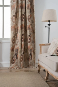 Detail of beige jacquard curtain featuring abstract oval patterns and white tassel fringe edge