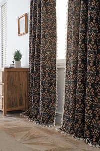 Close-up of black floral jacquard curtain with orange flower patterns and white tassels