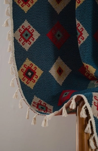 Detail of blue geometric woven curtain with tassel fringe and ethnic diamond pattern