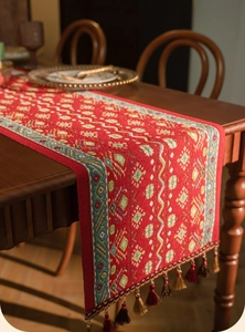 Detail of red table runner featuring complex jacquard patterns and decorative tassels