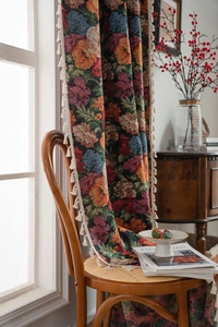 Close-up of floral jacquard curtain fabric with decorative off-white fringe tassels