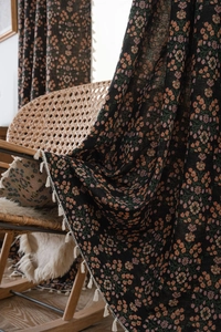 Close-up of black floral jacquard curtain fabric with decorative white fringe tassels
