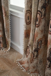 Detailed view of jacquard curtain fabric with retro ring patterns and white side tassels