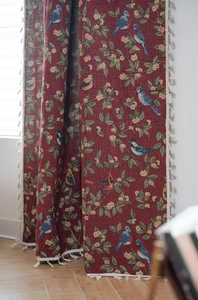Detail of red jacquard curtain featuring floral bird embroidery and cream fringe tassels